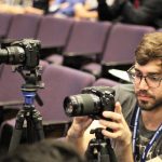 student with camera equipment at a conference